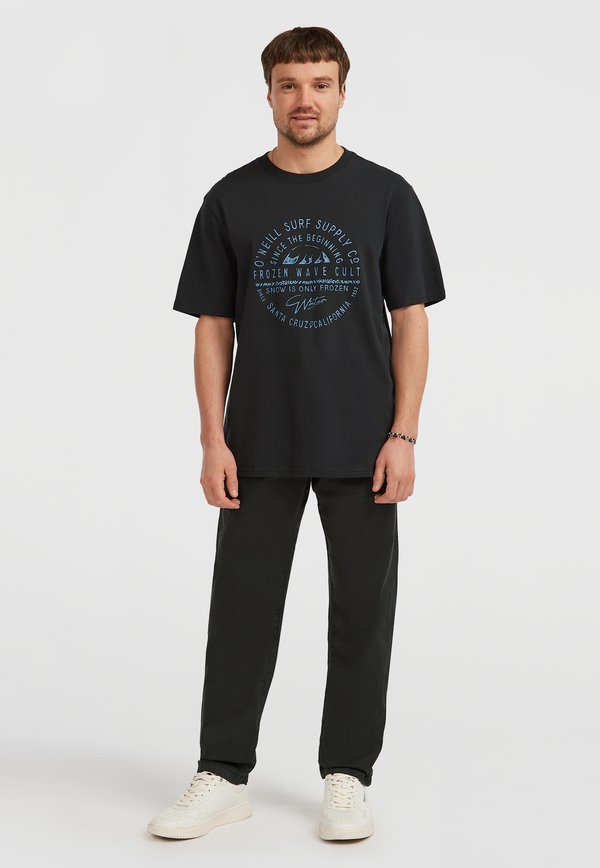 Melna kokvilnas T-krekls ar īsām piedurknēm, kuram ir zils grafisks teksts un okeāna tēmas dizaini. Apvienots ar tumši zaļām biksēm un baltām kedām.