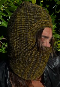 Knitted balaclava in dark brown and mustard yellow, featuring a seamless design with an eye opening, textured fabric, and a close-fitting shape.
