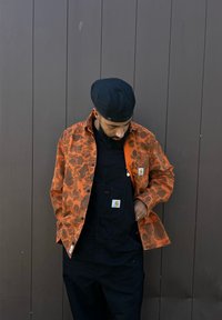 Παλτό με πορτοκαλί σχέδιο και μαύρη φόρμα. Το παλτό διαθέτει σχέδιο λεοπάρ και λεπτομέρειες με κουμπιά. Η μαύρη φανέλα ολοκληρώνει το σύνολο.