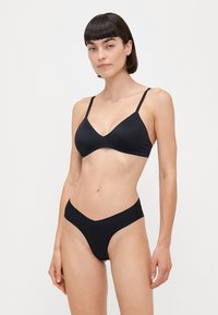 Μαύρο μπικίνι σετ που περιλαμβάνει ένα τριγωνικό μπραλέτ με λεπτές τιράντες και χαμηλοκάβαλο σορτς. Απαλή, ελαστική ύφανση με μίνιμαλ σχέδιο.