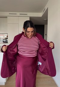 Pitkä viininpunainen hame, jossa on burgundy-takki, ja alla vaaleanpunainen ja tummanpunainen raidsaito-paita. Pehmeä kangas.