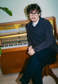 Trekksklaver med gylden innside, med svarte og hvite tangenter. En person i en mørk skjorte sitter ved siden av på en brun krakk. Grønn plante er synlig.