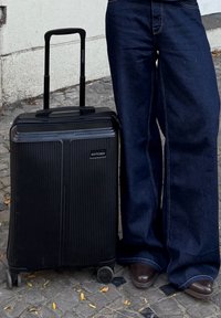 Valise rigide noire avec un design côtelé, poignée rétractable et roues. Logo WITTCHEN visible à l'avant. Surface texturée.