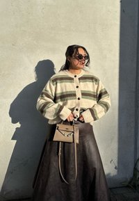 Prúžkovaný kardigán v krémovej, zelenej a hnedej farbe, s veľkými gombíkmi. Skombinujte s tmavou koženou sukňou a malou, štruktúrovanou kabelkou.