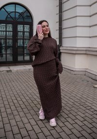 Pull en tricot marron et jupe assortie avec un motif texturé. Tissu doux, coupe décontractée, assortis à des baskets roses et une pochette rose.