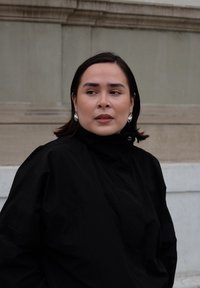 Veste noire à col montant avec une coupe décontractée, portée sur un col roulé, agrémentée de boucles d'oreilles argentées brillantes comme accessoires remarquables.