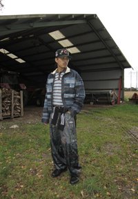 Džínová bunda s pásikavou košeľou pod ňou, maskáčové nohavice a baseballová čiapka, s rôznymi materiálmi, vzormi a farbami.
