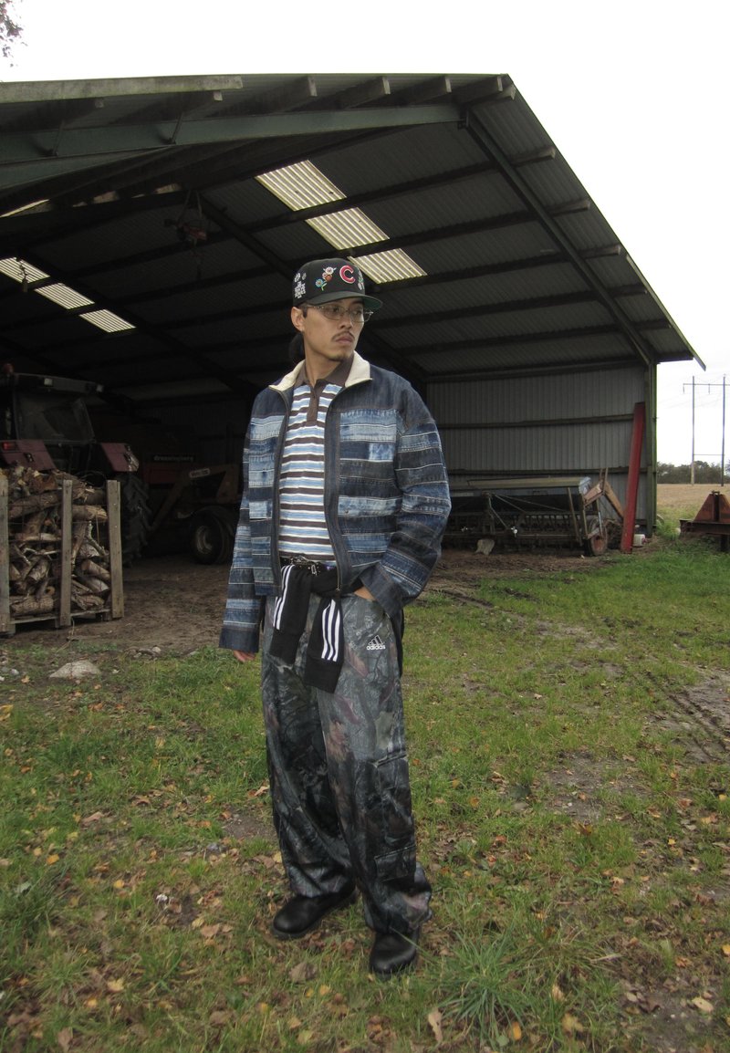 Denim jacket with striped shirt underneath, camo pants, and a baseball cap, featuring various materials, patterns, and colors.