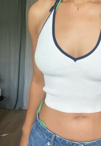Balta īsā topiņš ar ribotu tekstūru, tumši zils apmale ap kaklu un halteru siksnām. Savai izskatam pievienoti zili denim šorti.