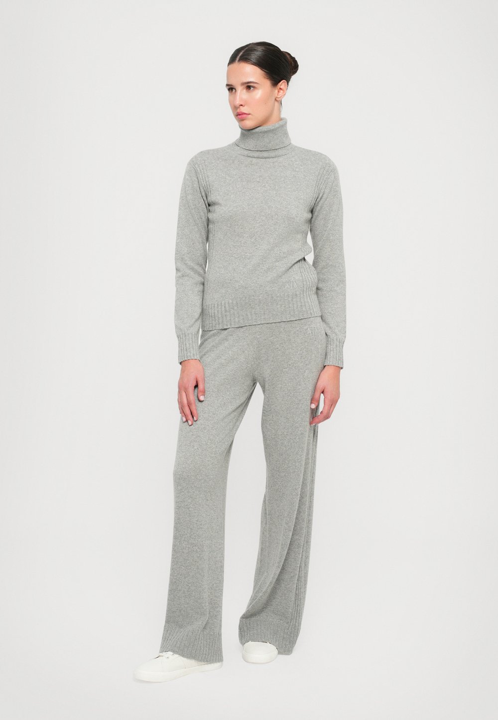 Grey knitted turtleneck sweater paired with matching grey wide-leg trousers. The fabric looks soft, featuring ribbed cuffs and a simple design.