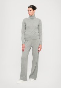 Grey knitted turtleneck sweater paired with matching grey wide-leg trousers. The fabric looks soft, featuring ribbed cuffs and a simple design.