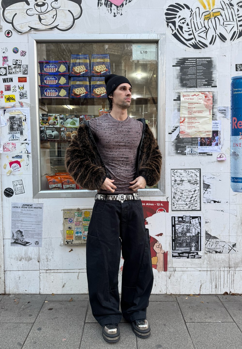 Long-sleeve, patterned grey shirt worn beneath a brown fur jacket, teamed with black wide-leg trousers and chunky black shoes featuring metallic accents.