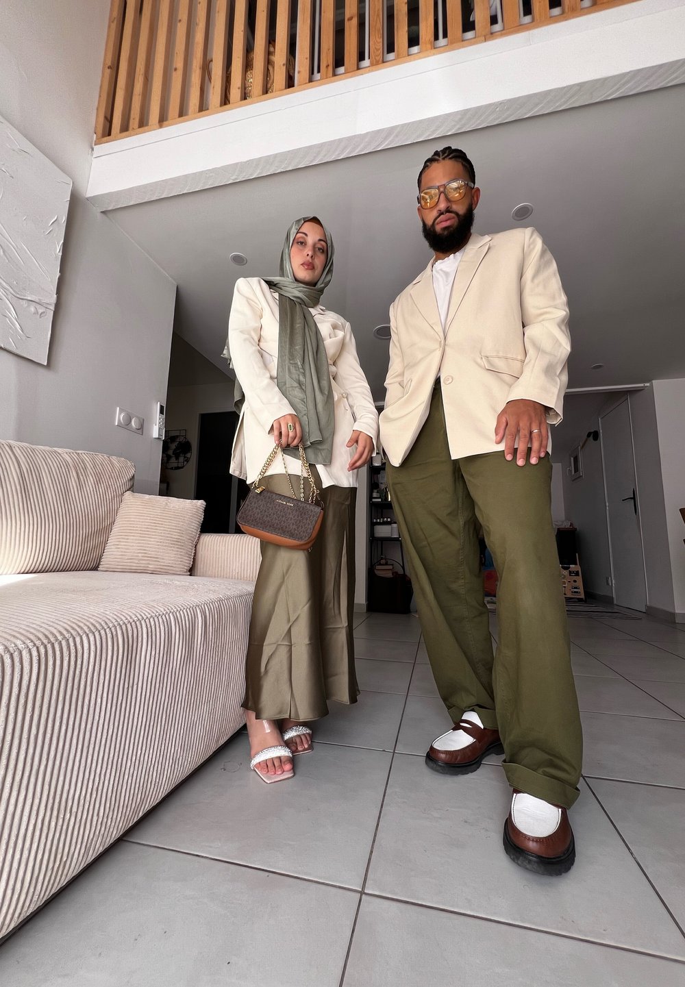 Ανοιχτό μπεζ σακάκι, ελαιόφωνες παντελόνα πλατιάς γραμμής και υφασμάτινη καφέ τσάντα. Το μοντέλο φοράει χιτζάμπ και σανδάλια με κρυσταλλική λεπτομέρεια.