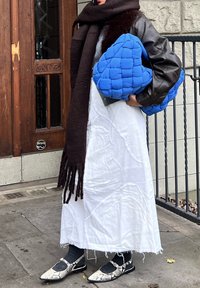 Tikitud sinine käekott, pruun sall, hall särk, valge tekstuuriga kleit ja mustad madalad kingad koos lõikega ning madu mustriga.