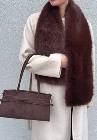 Pruun kunstkarvaga sall, mis on heleda beežika riidest mantli peale lootud, kombineeritud väikese pruuni käekotiga, millel on tekstureeritud pind ja kaks käepidet.