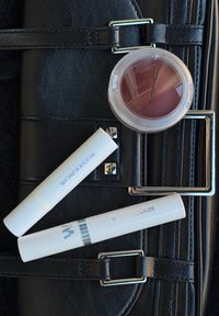 Trois produits cosmétiques sur une surface texturée noire : deux tubes blancs étiquetés "Wonderskin" et un contenant transparent avec un blush crème bordeaux de MAC.