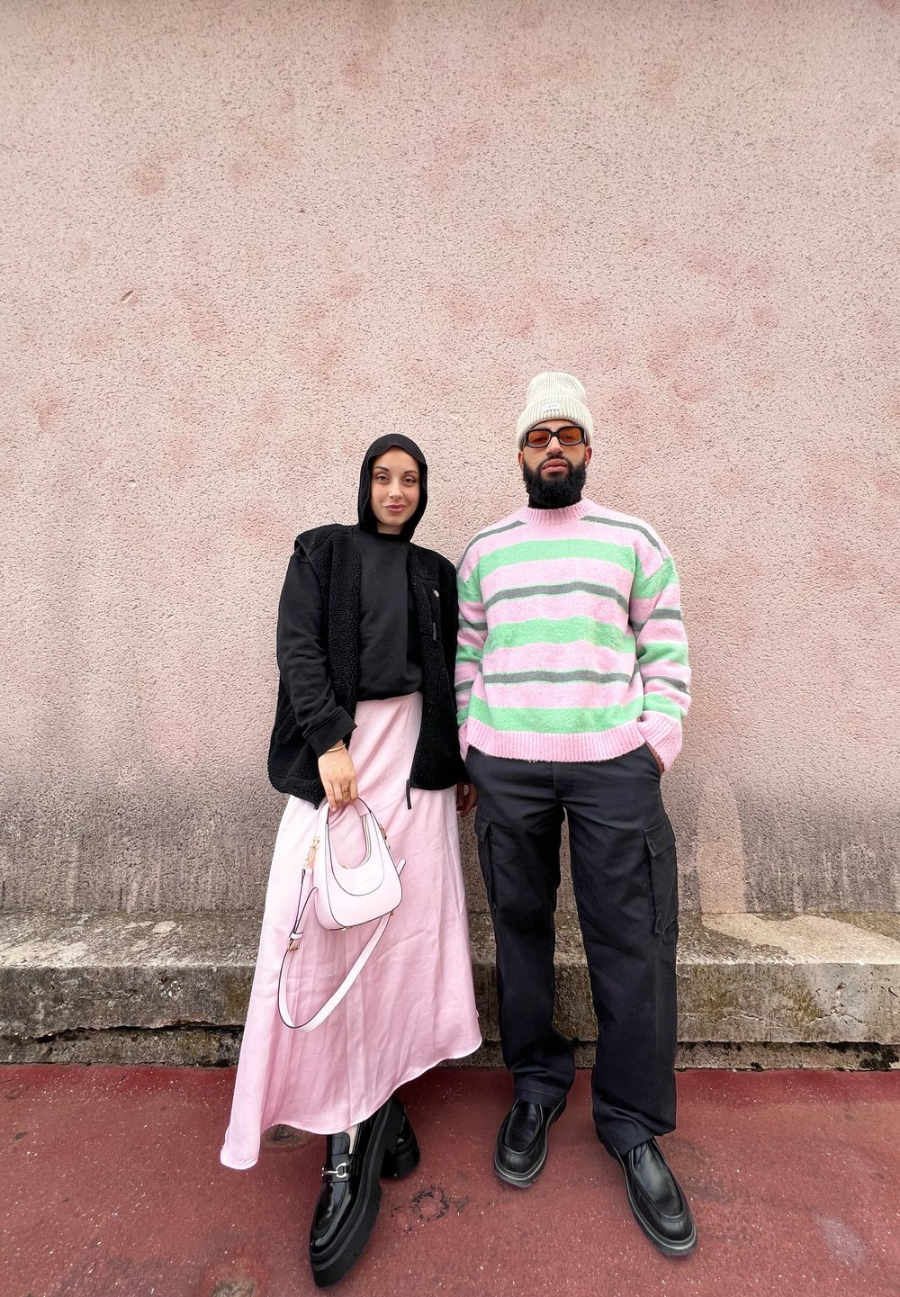 Μαύρο φούτερ με φερμουάρ, ροζ φούστα και μικρή ροζ τσάντα στα αριστερά; ριγέ παστέλ πουλόβερ και μαύρο cargo παντελόνι στα δεξιά.