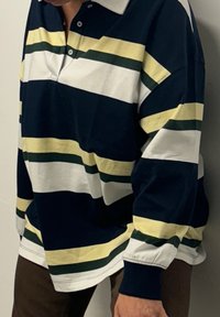Langarm-Polohemd mit horizontalen Streifen in Navy, Weiß und Grün. Verfügt über einen Kragen und eine Zwei-Knopf-Leiste. Weicher Baumwollstoff.
