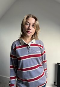 Langermet polo skjorte i grå med røde og hvite horisontale striper, med hvit krage og en subtil logo på brystet.