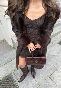 Brun blondelkjole med en tettsittende silhuett, parret med en lang brun frakk med kunstpels på ermene. Tilbehøret inkluderer en burgunder veske og støvler.