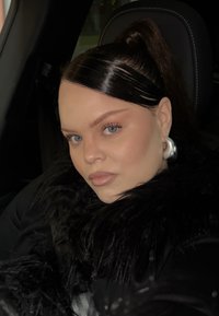 Sort pelskkrave med en blank sort frakke; glat, lige hår med en høj hestehale; sølv ørering i form af en ring; lys hud og blå øjne.