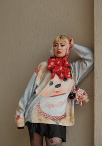 Oversized-Pullover mit einem Plüschpuppen-Motiv in Pastellfarben. Mit gerippten Bündchen, abgerundetem Saum und weichem Material. Abgerundet mit einem roten Schal und Taschenanhängern.