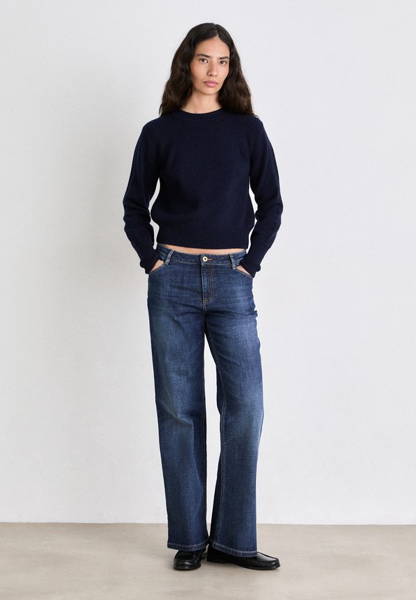 Marineblå strikket sweater med rund hals, parret med vidde bukser i mørkeblå farve, der har knaplukning og frontlommer. Glat tekstur hele vejen igennem.