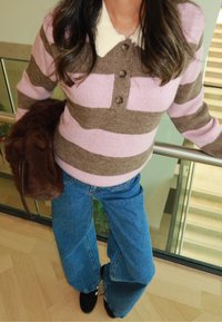 Brun og lyserød stribet strikket sweater med knapper, lysefarvet krave, kombineret med vidbenede blå jeans og en brun pels taske.