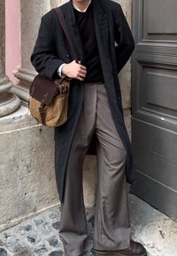 Melnas vilnas virsjakas pārklājums virs melna džempera, apvienots ar pelēkām platām biksēm. Brūna ādas sūtījumu soma ar auduma ķermeni un brūniem akcentiem.