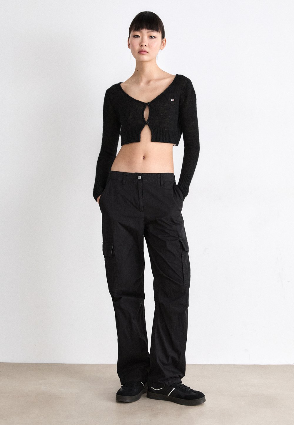 Woman wearing black cargo pants with a cropped cardigan