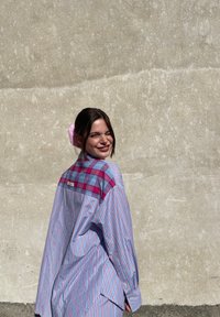 Plava i roza prugasta košulja s karo jastučićem, dugih rukava, širokog kroja i kontrastnim uzorcima.