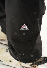 Zwarte sneeuwbroek met een driehoekige O'Neill-logo patch met een kleurrijk ontwerp. De stof lijkt glad en geschikt voor winteractiviteiten.