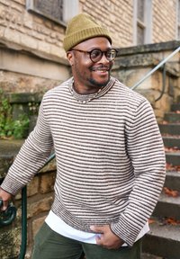 Knit jumper with horizontal brown and beige stripes, round neckline, and textured fabric, paired with an olive green beanie and layered shirt.