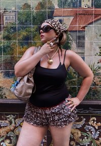 Top noir sans manches et shorts à volants imprimé léopard ; accessoirisé avec des lunettes de soleil, un foulard, des colliers superposés et des bagues à déclaration.