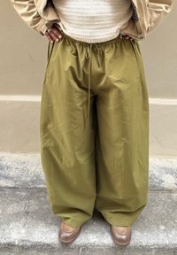 Olijfgroene, wijdvallende broek met elastische tailleband en trekkoord; lichtgewicht stof met een gladde textuur.