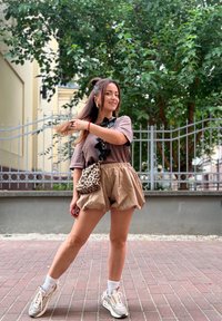 Μπεζ σορτσάκια με βολάν στο τελείωμα, σε συνδυασμό με καφέ μπλούζα με βολάν στον λαιμό. Τα αξεσουάρ περιλαμβάνουν τσάντα με λεοπάρ σχέδιο και αθλητικά παπούτσια.