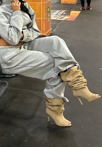 Šedé tepláky a odpovídající zkrácená mikina doplněné béžovými volnými vysokými podpatky. Outfitu dominují pohodlný střih a měkká textura.