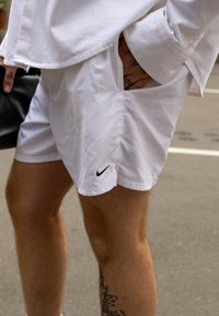 Shorts bianchi Nike con un logo nero sull'orlo inferiore. Il tessuto appare leggero e liscio, aderente al corpo.