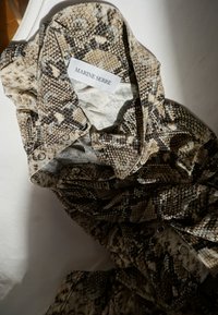 Skjorta mönstrad med ormskinn av Marine Serre, med en huva, knappar och en blandning av bruna och beige nyanser. Mjukt tyg med texturerad detalj.