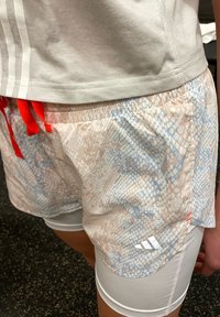 Pantalones cortos ligeros, con un diseño estampado en colores pastel y un patrón de piel de serpiente, que cuentan con cordones rojos y pantalones interiores blancos.