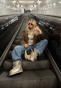 Smeđi janjeći kaput, sivi pulover i oversized svijetloplave traperice. Nosim sive čizme s teksturiranim potplatima, držeći bež torbu.