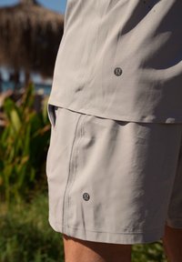 Light gray athletic shorts made of breathable fabric, featuring a small logo on the side and a flat waistband with pockets.