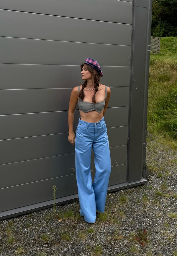 Un haut court gris, un pantalon large bleu clair et un béret à carreaux. Textures lisses, détail de boutons sur le haut et coupe décontractée pour le pantalon.
