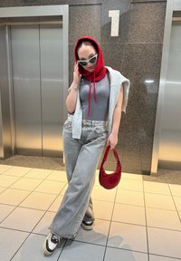 Grå heldragt, oversized lysegrå strikket sweater, rød hætte, lysegrå jeans med vide ben, rød håndtaske, sorte solbriller, sneakers med plateau.