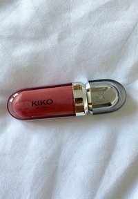 Gloss à lèvres KIKO Milano dans un contenant transparent bourgogne, avec un capuchon argenté et une formule rose scintillante.