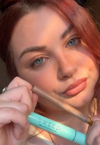 NABLA Cupid's Arrow Augenbrauenstift in Hellbraun und SWEED Pro Lash Lift Mascara in Minzgrün, gehalten vor einem Hintergrund in natürlichem Hautton.