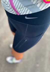 Ρούχα γαλάζιου χρώματος Nike κολάν με στενή εφαρμογή, διαθέτοντας μια μικ ρή θήκη με φερμουάρ και ένα ανοιχτό γκρί λογότυπο στη μέση.