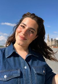 Chemise en jean à boutons avec deux poches avant, de couleur bleu profond, dotée de boutons-pression argentés et d'un col, sur fond de ciel bleu.