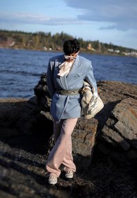 Hele sinise bleiseri struktuurne õlgadega, beežsiidist sall, pehmed roosa laia säärega püksid ja kreemivärvi käekott mustriga aktsendiga.