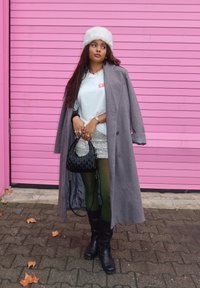 Γκρι παλτό, λευκό μπλουζάκι με κόκκινο κείμενο, λαμπερή ασημένια μίνι φούστα, πράσινες καλσόν, μαύρες μπότες έως το γόνατο και μια μαύρη υφασμάτινη τσάντα. Λευκό καπέλο με γούνα.